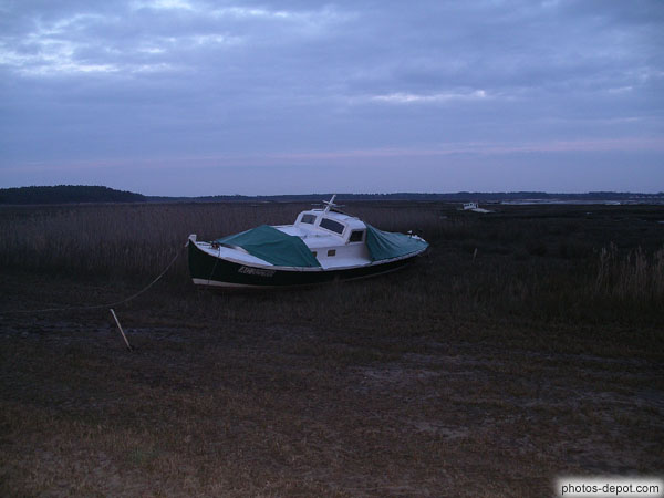 photo de bateau amaré reposant sur le sol à marée basse dans le bassin