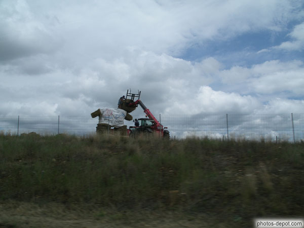 photo de tracteur posant un round-baller en guise de tête à un énorme bonhomme