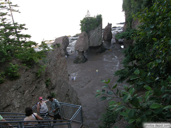photo de rochers dressés sur la grève et escalier de descente sur la plage