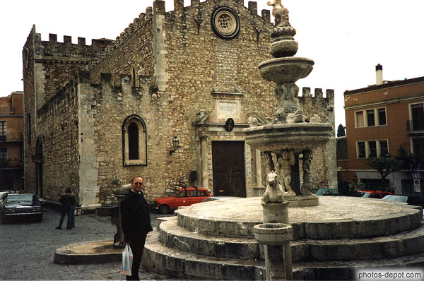 photo d'eglise aux murs crénelés et ancienne fontaine bétonnée
