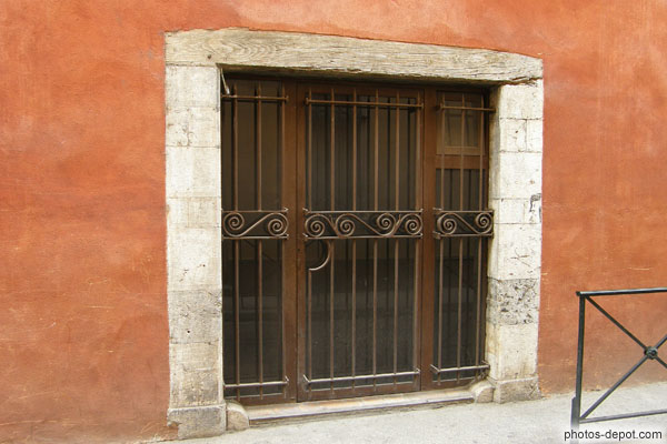 photo de porte fenêtre à grille, linteau de bois et mur rouge