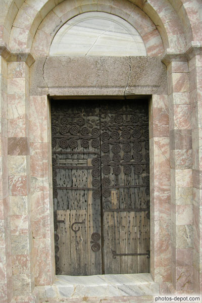 photo de Pentures typiques catalanes à spirales symétriques et cloutées dans le bois décorant et renforçant la porte.