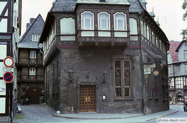 photo d'auberge aux beaux balcons de bois travaillé sur murs de pierre noircis