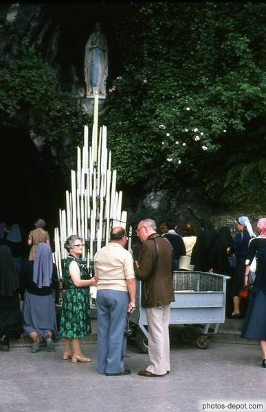 photo de cierges allumés devant la statue de la Vierge au dessus de la grotte