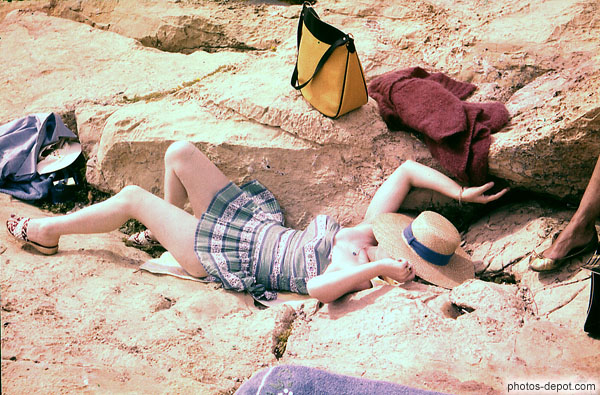 photo de femme allongée sur le rocher en robe légère et chapeau de paille