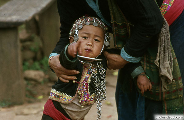 photo d'enfant tête couverte d'un pendentif de pièces, montre du doigt