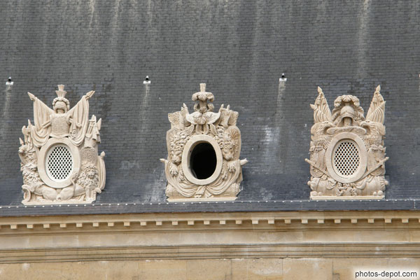 photo de fenêtres rondes ornées de blasons dans le toit des Invalides
