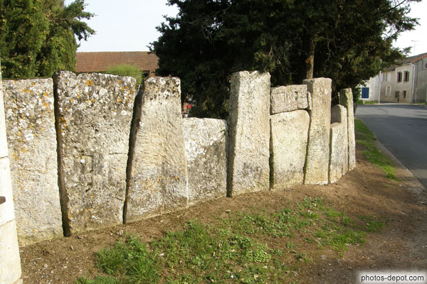 photo de pierres tombales fichées en terre tiennent lieu de mur au cimetière mérovingien