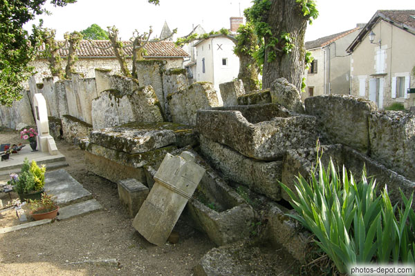 photo d'empilement de sarcophages chrétiens mérovingiens abandonnés formant le mur du cimetière