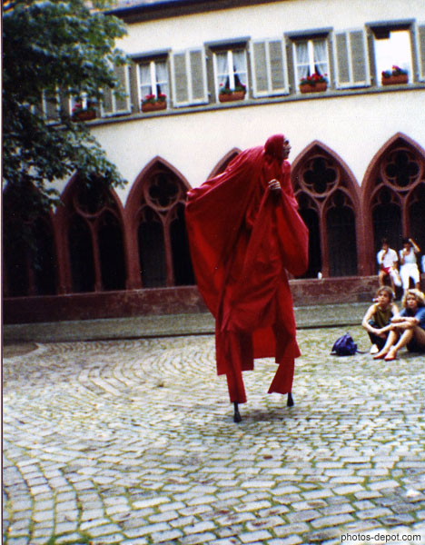 photo d'homme en rouge sur échasses