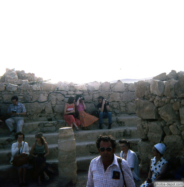 photo de touristes assis sur les marches devant le mur